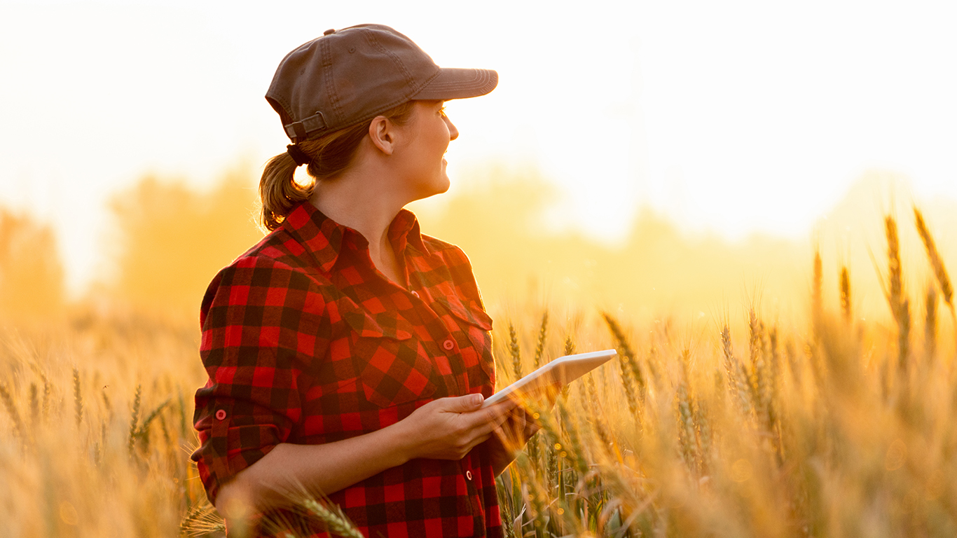 Woman standing in wheat field with tablet