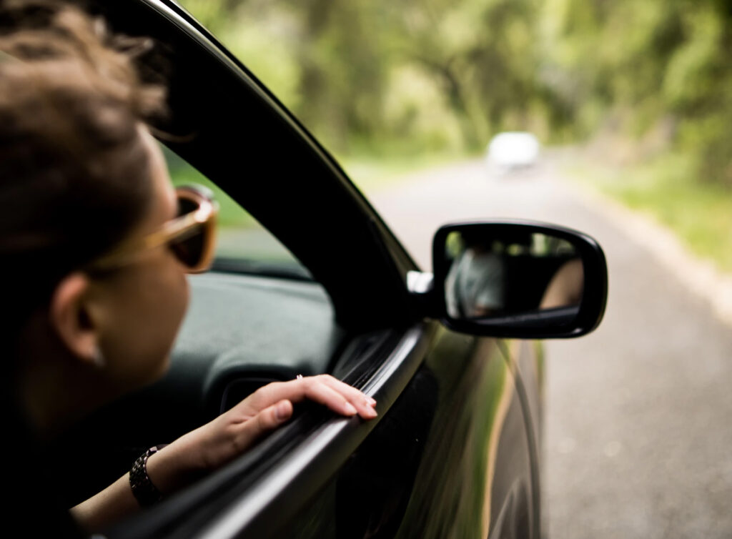 photo of woman keeping her head out of a moving car